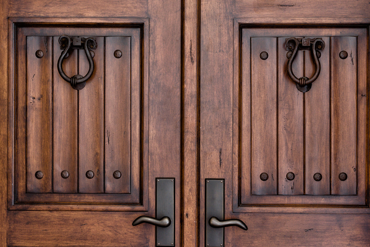 Paneled wooden double doors with wrought iron knockers