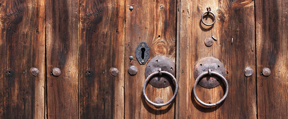 Weathered wooden plank door with hand-forged iron ring pulls